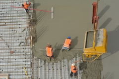 Construction builders applying and leveling cement in building site