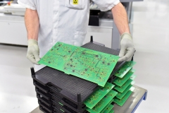 Arbeiter hält Platine mit Mikroelektronik in einer Fabrik - Produktion von High Tech Bauteilen // Worker holding circuit board with microelectronics in a factory - production of high tech components