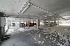 parking garage with several cars parked inside. The floor is wet with melting snow
