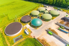 Aerial view over biogas plant and farm in green fields. Renewable energy from biomass. Modern agriculture in Czech Republic and European Union.