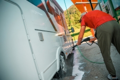 Man Washing His Camper Van at a Local Service Station During Sunny Afternoon