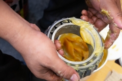 Senior worker putting lubricant lithium grease (NLGI 3) into wheel bearing for ten wheel truck car by hand at service station in Asia. Grease appearance is yellow. Maintenance and preventive concept.