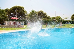 Kid jumping into a pool creating a giant water splash. Beautiful weather, summertime ! Very bright and colorful shot, clear blue water. Beautiful sunny day. Alcossebre, Valencia Community, Spain