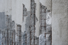 Damaged concrete walls with exposed steel reinforcements inside.