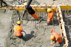 Street workers pouring cement with a pump into a highway construction