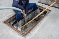 A man is carrying a suction hose from the Waste Water Treatment Plant to the suction truck.