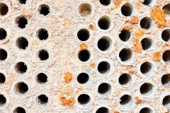Selective focus tube sheet or boiler or plate of heat exchanger closeup texture macro diagonal background full of hard insoluble mineral deposits salts scale and corrosion. Trypophobia concept.
