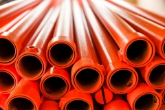 Metallic pipes covered with orange paint. Background with perspective. Selective focus.